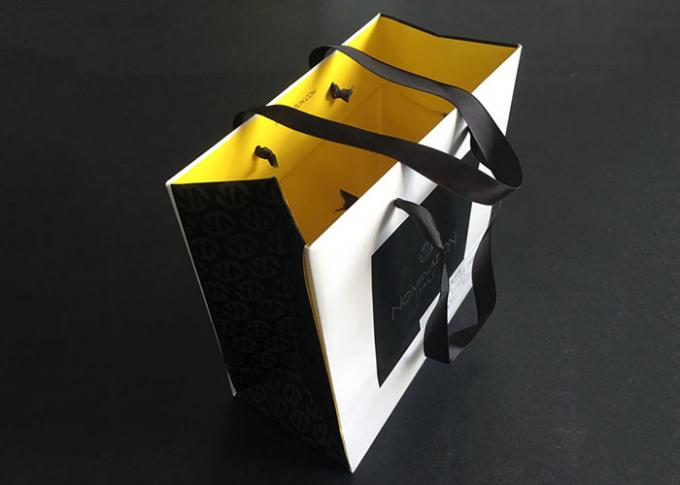 リボンのハンドルのギフトによって印刷される紙袋はグリースを弾く白い黒の内部の黄色を運びます